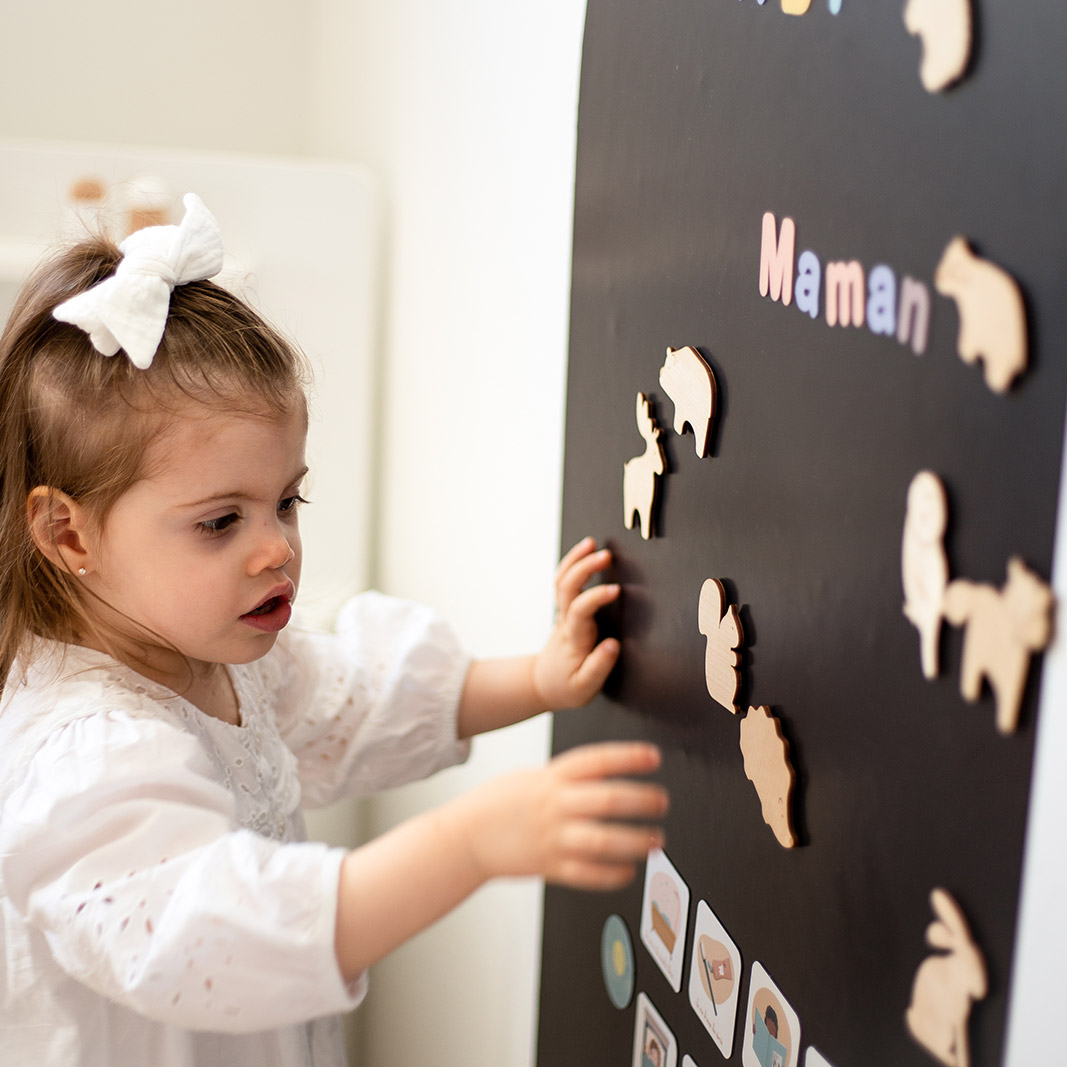 Petite fille qui joue avec des magnets en bois en forme d'animaux.